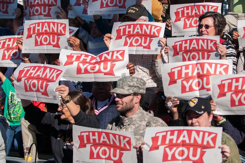 5 Facts About Veterans Day 5 Crowd holds up several thank you signs.
